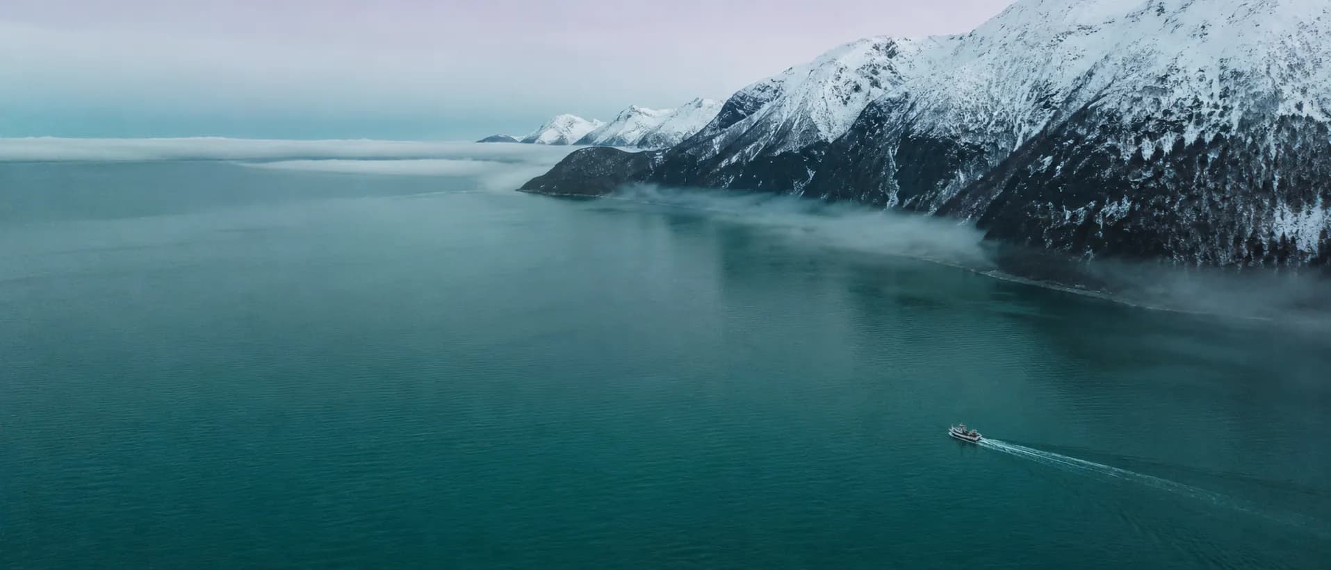 Norwegian Arctic fjord with fishing vessel and snow-capped mountains